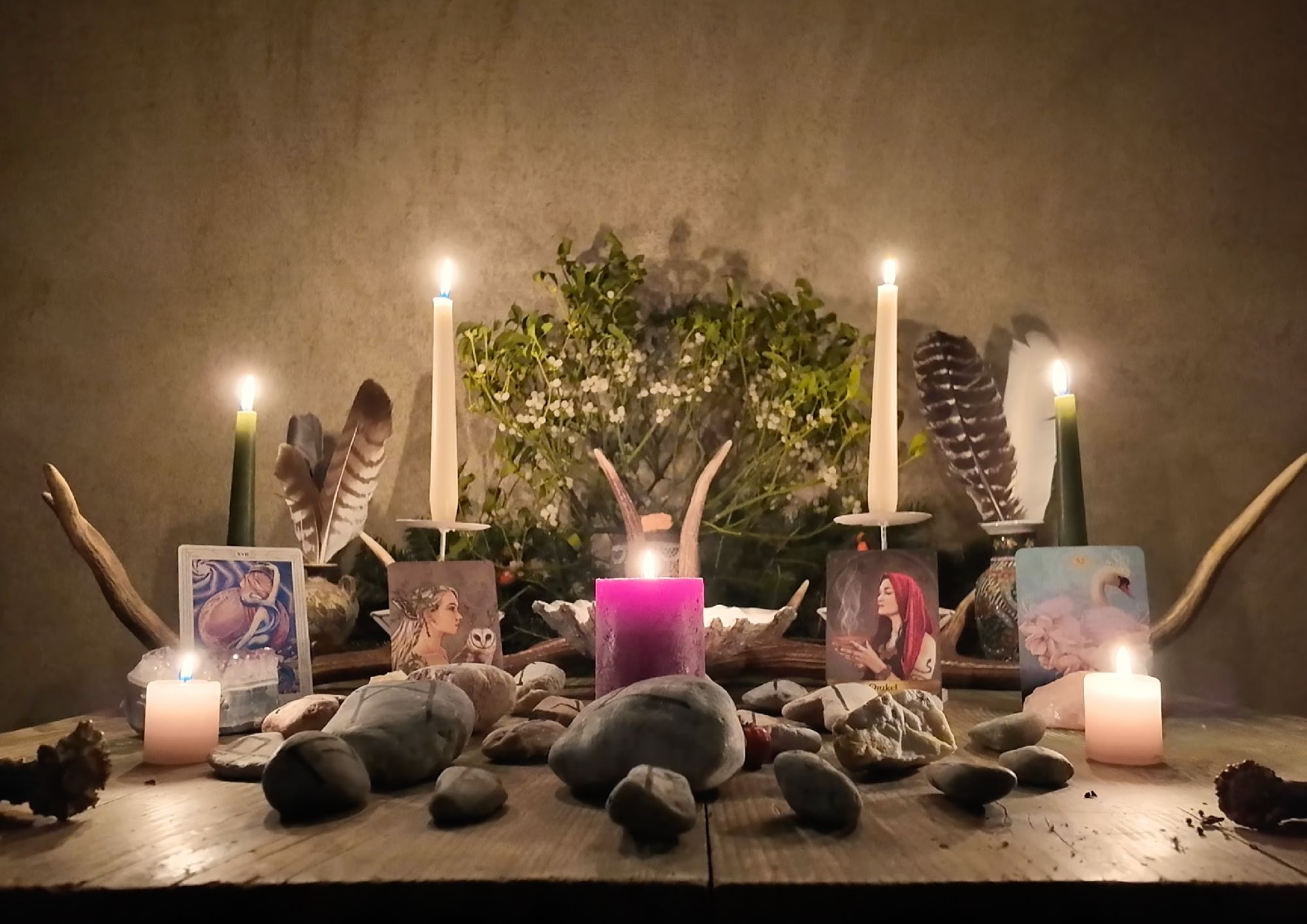 Rauhnächte Altar mit Kerzen Runensteinen Tarot Federn Misteln in den Alpen